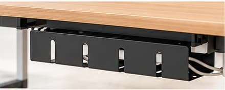 Black metal cable management tray mounted under a wood desk